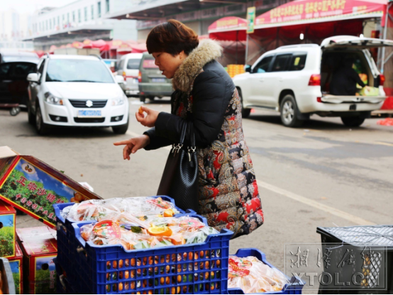 湘潭金阳城散货区里，一位大姐正在试吃沙糖桔（记者 李蓓 摄）